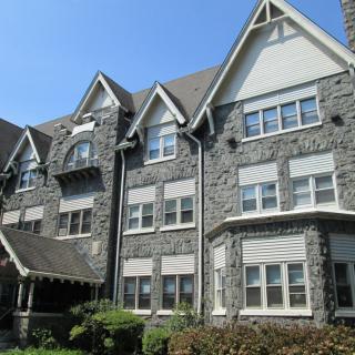 A beautiful stone residential building featuring a Gothic architectural style with multiple peaked roofs and numerous windows.