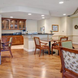 A cozy dining area with wooden flooring, featuring elegant furniture and a bar counter.