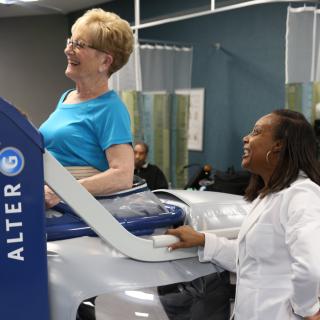 A physical therapist assists a woman using specialized rehabilitation equipment.
