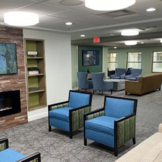 A modern lobby featuring comfortable blue chairs, a cozy fireplace, and a welcoming atmosphere.