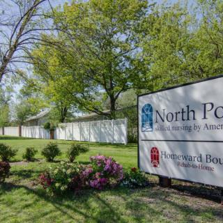 Entrance sign for North Point Cemetery surrounded by trees and landscaped flowers.