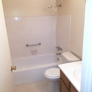 A small bathroom with a bathtub, shower, toilet, and sink.