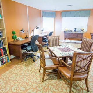 A cozy office space with desks, chairs, and a bookshelf.