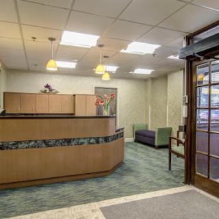 A spacious and welcoming reception area featuring a wooden desk and comfortable seating.