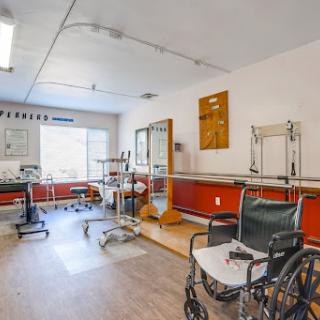 A spacious rehabilitation room equipped with a wheelchair and various therapy tools.