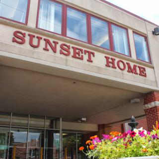 The entrance of Sunset Home, featuring vibrant flowers and a welcoming facade.