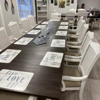 A neatly arranged dining table with white chairs and placemats in a cozy indoor setting.