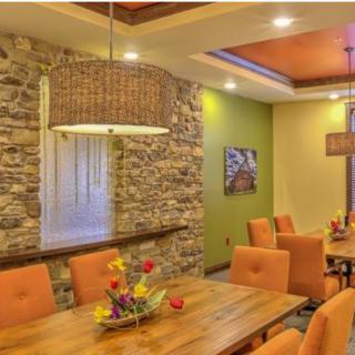A modern dining room with a stone accent wall and vibrant orange chairs.