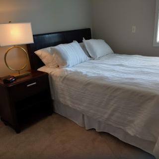 A cozy bedroom setup featuring a neatly made bed and a stylish nightstand with a lamp.