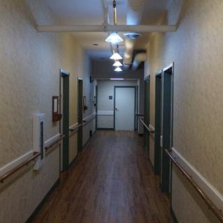 A dimly-lit hallway with multiple doors and overhead lighting.