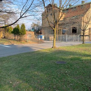 A view of a building surrounded by trees and grass, with a road leading into the scene.