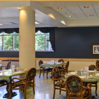A spacious restaurant interior with elegant tables and chairs, surrounded by large windows.