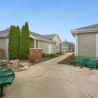 A peaceful residential pathway surrounded by greenery and benches.