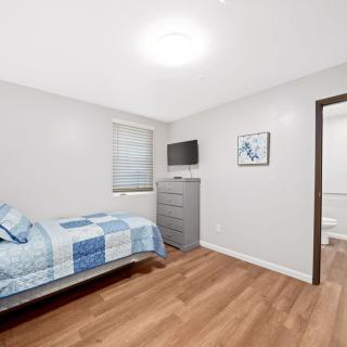 A minimalist bedroom with a single bed, wooden flooring, and modern decor.