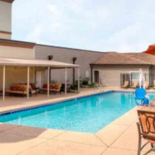An inviting outdoor swimming pool with surrounding seating and a shaded patio.