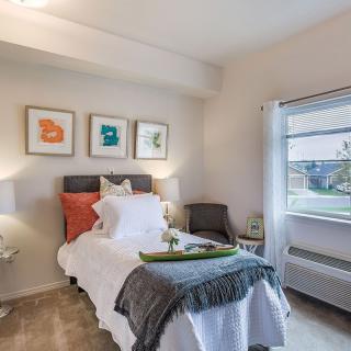 A modern and cozy bedroom with minimalist decor, featuring a comfortable bed, artwork on the wall, and natural light from the window.