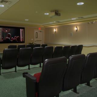 A cozy home theater setup with rows of comfortable seating facing a large screen.