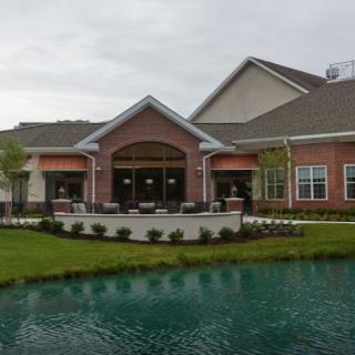 A residential building with a landscaped garden and pond in the foreground.