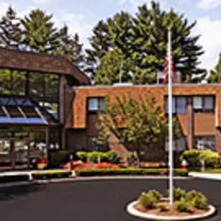 A brick building with a flagpole in front, surrounded by trees and landscaping.
