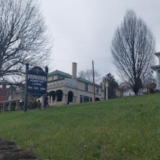 A charming historic building with a sign, set against a backdrop of bare trees and a cloudy sky.