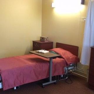 A simple bedroom with a single bed, nightstand, and small table.