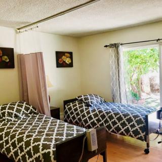 A cozy bedroom with twin beds and a view of the garden through a large window.