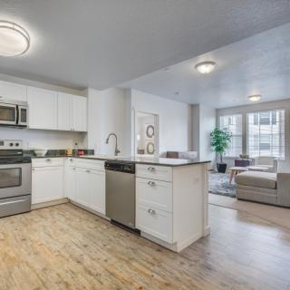 A modern, open-concept kitchen and living room with stainless steel appliances and hardwood flooring.