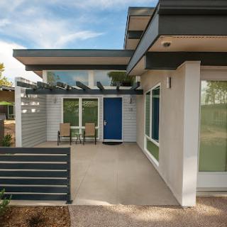 A stunning modern house with a vibrant blue door and inviting outdoor seating on the porch.