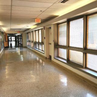A quiet and well-lit hallway featuring large windows.