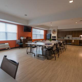 A modern open-plan kitchen and dining area with tables, chairs, and large windows.