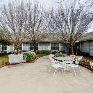 A cozy patio area with outdoor seating surrounded by trees and a garden.
