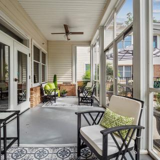 A cozy porch with comfortable seating and a ceiling fan, overlooking the outdoors.