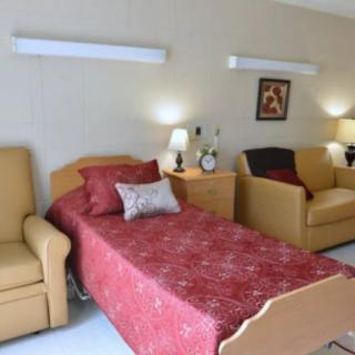 A cozy bedroom with a single bed, two armchairs, and soft lighting.