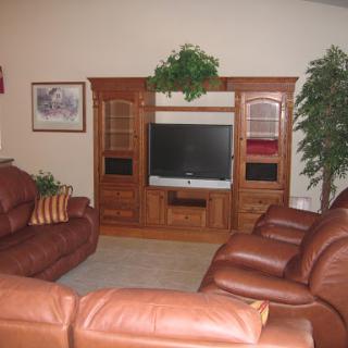 A cozy living room featuring a leather sofa arrangement and a wooden TV stand.