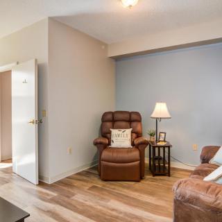 A cozy living room with a brown armchair, adjacent lamp, and wood flooring.