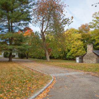 A peaceful autumn scene with a winding pathway surrounded by colorful trees and a small stone building.