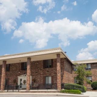 A two-story brick building under a partly cloudy sky.
