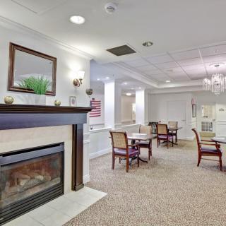 A cozy and elegantly furnished indoor space featuring a fireplace, tables, and chairs.