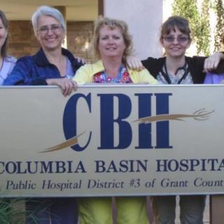 A group of people standing behind a sign for Columbia Basin Hospital.