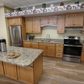 A modern kitchen with wooden cabinets and a granite island, featuring stainless steel appliances.