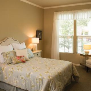 A cozy bedroom with a neatly made bed and a window letting in natural light.