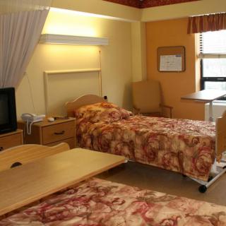 A hospital room with two beds and medical furniture.