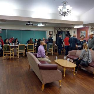 A lively gathering in a community center, with people engaged in conversation and enjoying the space.