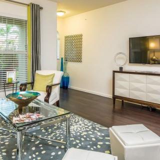 A modern living room with stylish furniture, a TV mounted on the wall, and a glass coffee table.
