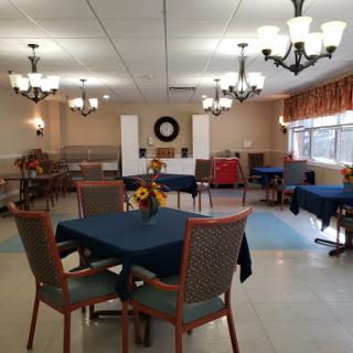 A spacious and inviting dining area featuring tables with blue tablecloths, decorative lighting, and a warm ambiance.