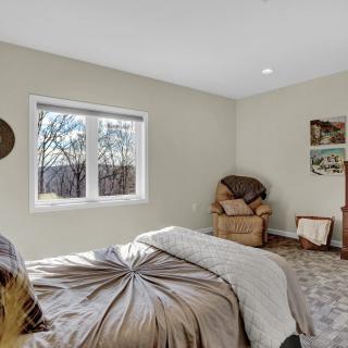A cozy bedroom with a bed, armchair, and window providing natural light.