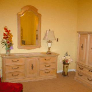 A well-appointed bedroom with a dresser, ornate mirror, lamp, and decorative elements.