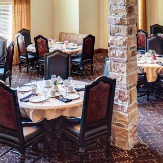 An elegantly set dining area with multiple round tables and classic chairs.