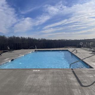 A serene outdoor swimming pool under a clear blue sky.