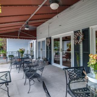 A cozy patio area with tables and chairs, surrounded by plants and large windows.